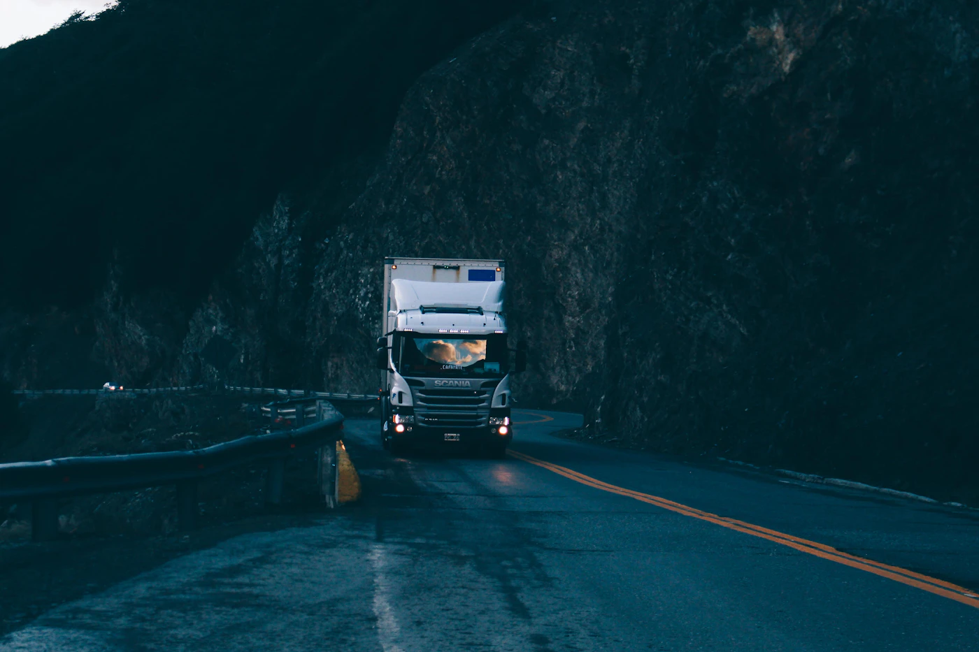 Truck driving through a mountain road at dusk