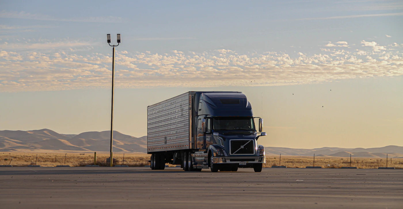 Modern Volvo semi-truck driving down a desert highway at golden hour