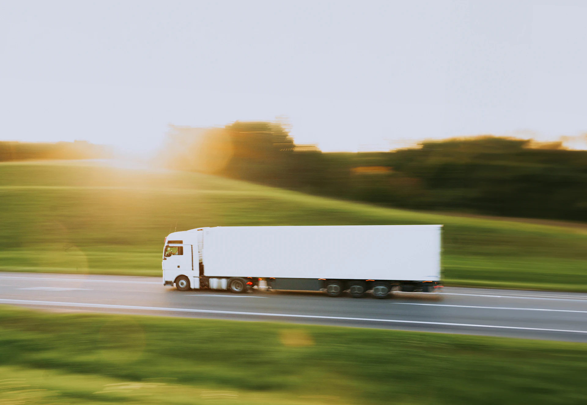Semi-truck driving down the highway at sunset