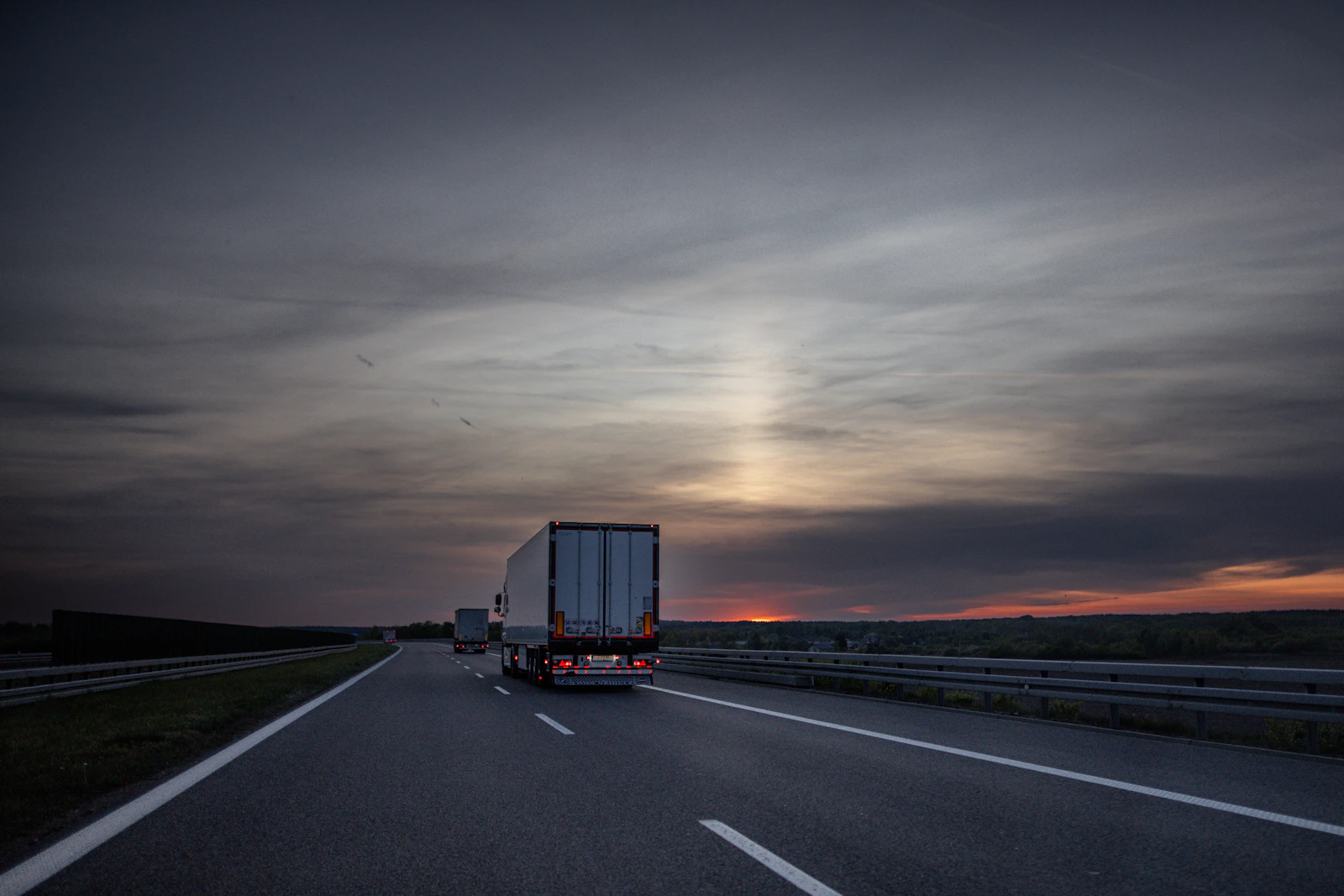 Trucks driving on a highway at sunset